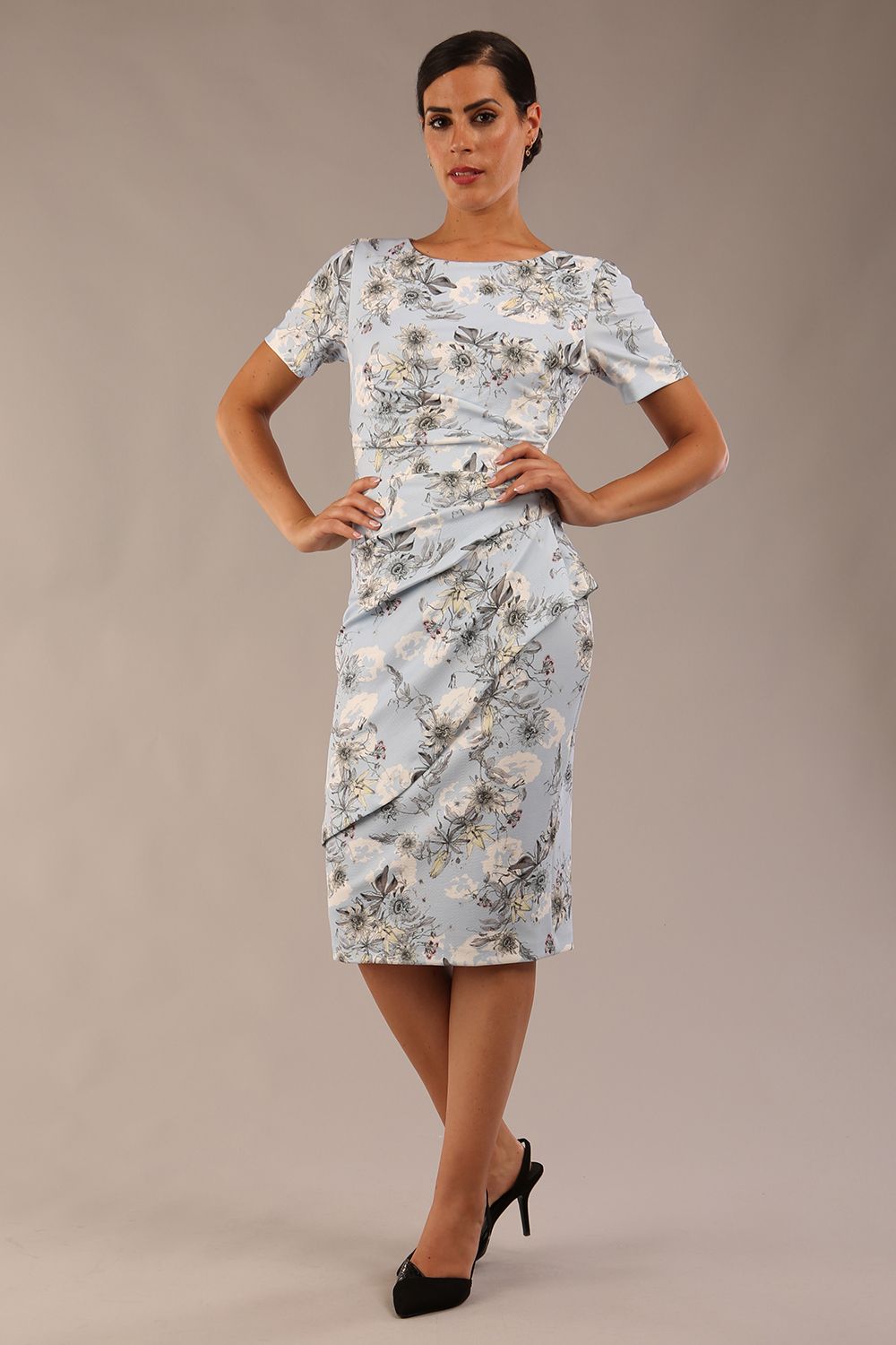 model wearing a  diva catwalk Katia pencil dress with a cascading layered skirt and stunning floral patterns with shor sleeves and knee length in botanical passion light blue print