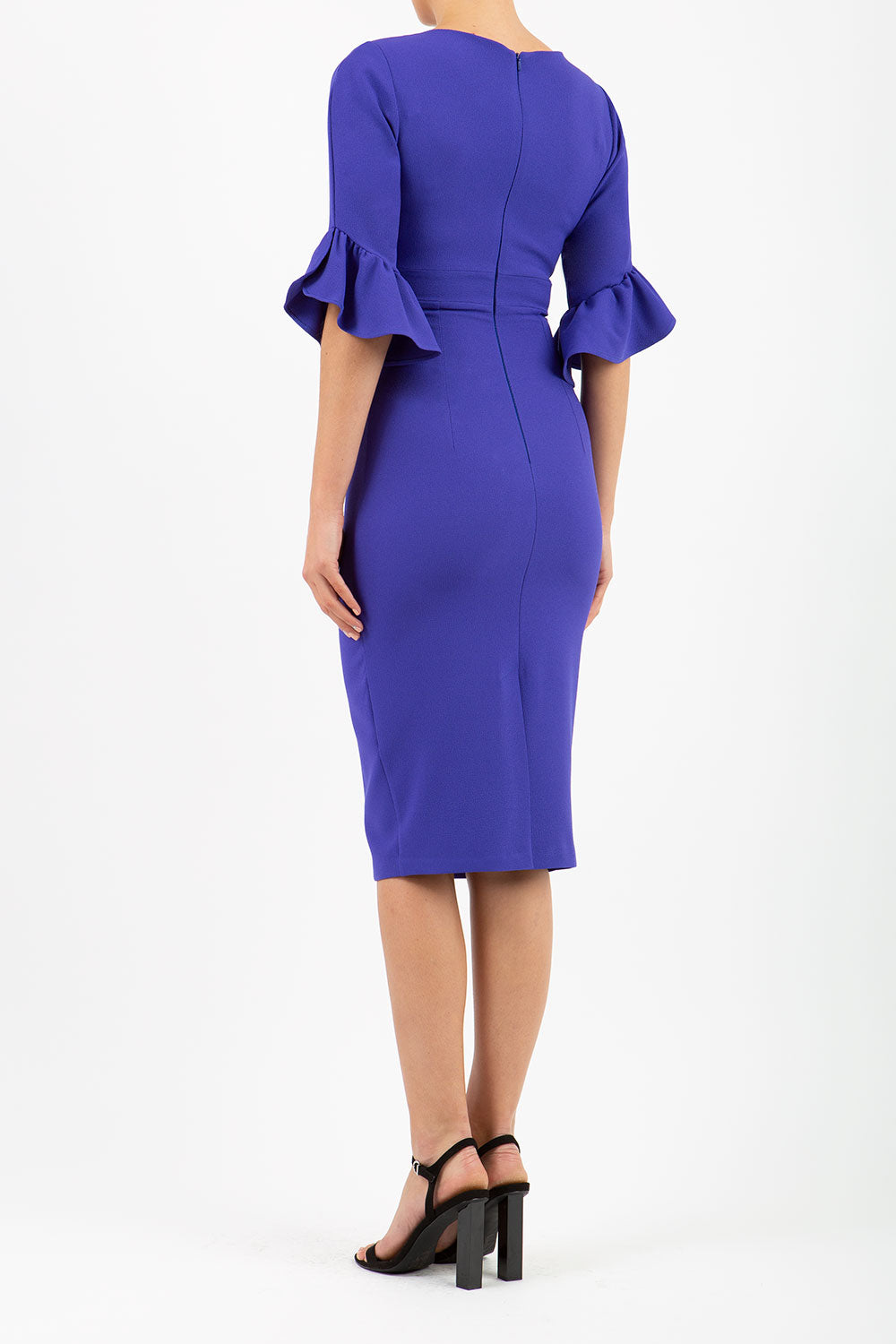 brunette model is wearing diva catwalk hollie pencil dress with frilled flute sleeve and low v-neck cut in indigo back