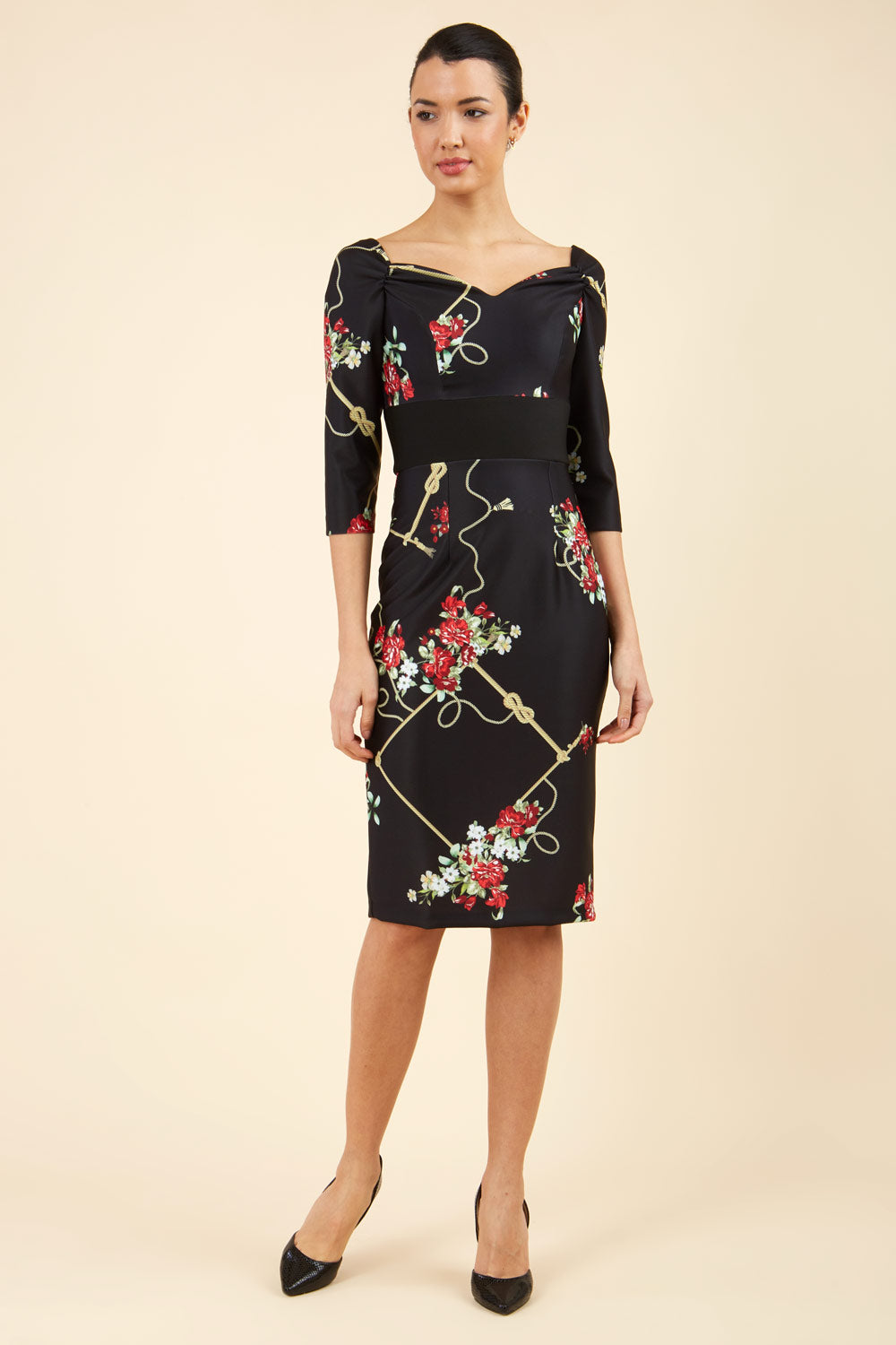 Brunette model is wearing Diva Catwalk Pencil Printed three quarter sleeved dress with wide black band and wide v neckline in Vintage Rose print front