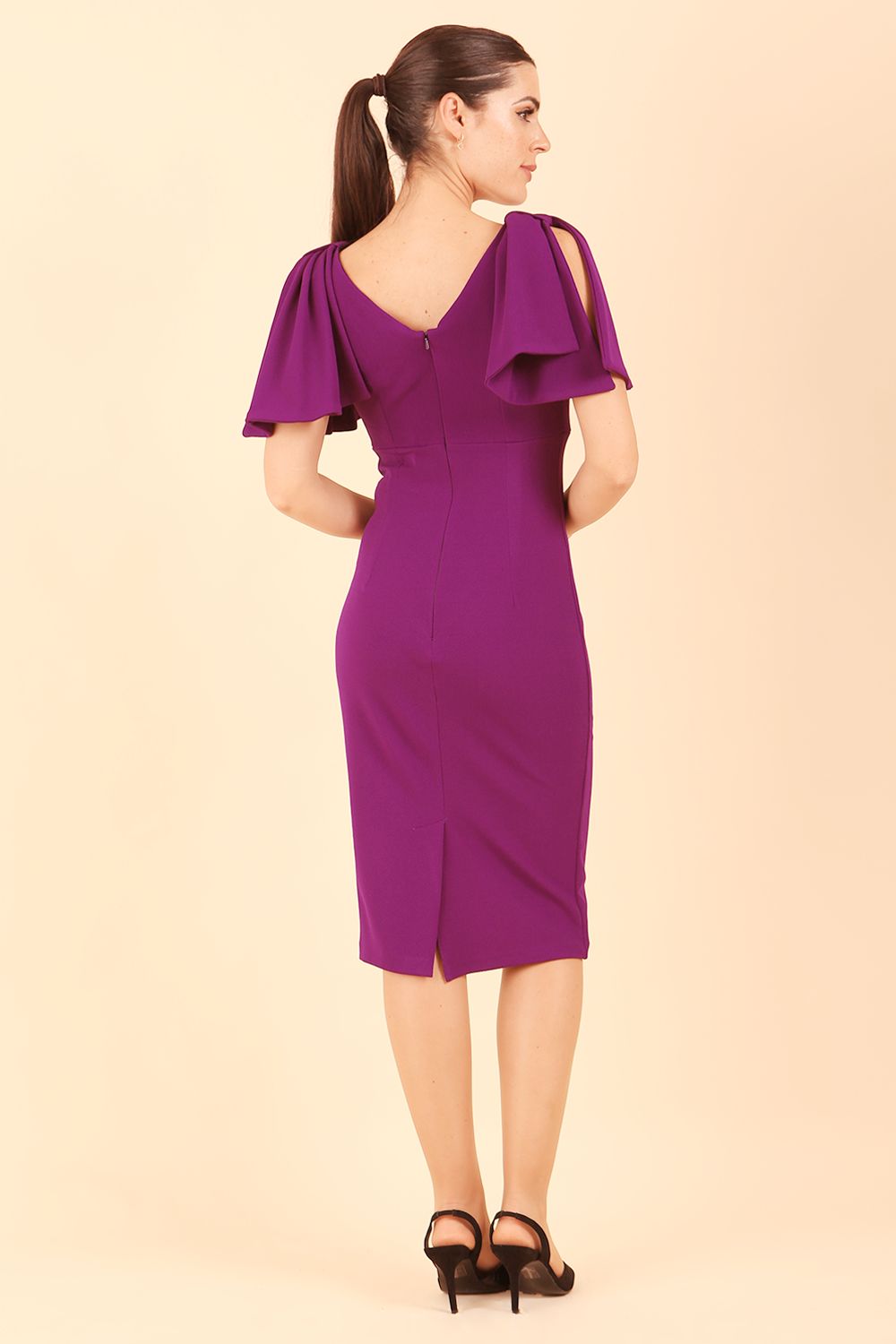 brunette model is wearing diva catwalk hermione pencil dress with tie shoulder details and empire waistline in Deep Purple back