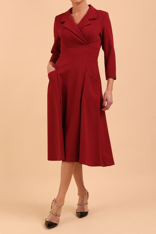 A model is wearing a swing wine three quarter sleeve dress with oversized collar and pockets in the skirt