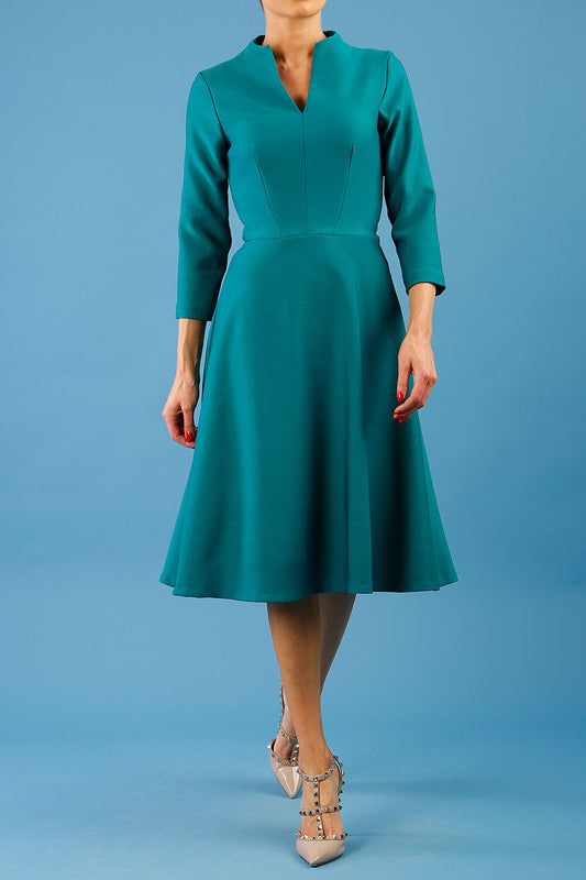 model is wearing diva catwalk palmerston vintage style a-line dress with sleeves and high neck with a slit in pacific green colour front