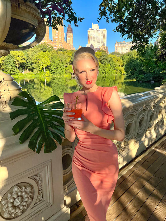 model wearing diva catwalk Bodiam Bodycon Pencil Dress with frill sleeves in knee length and pleating across the tummy in peach front