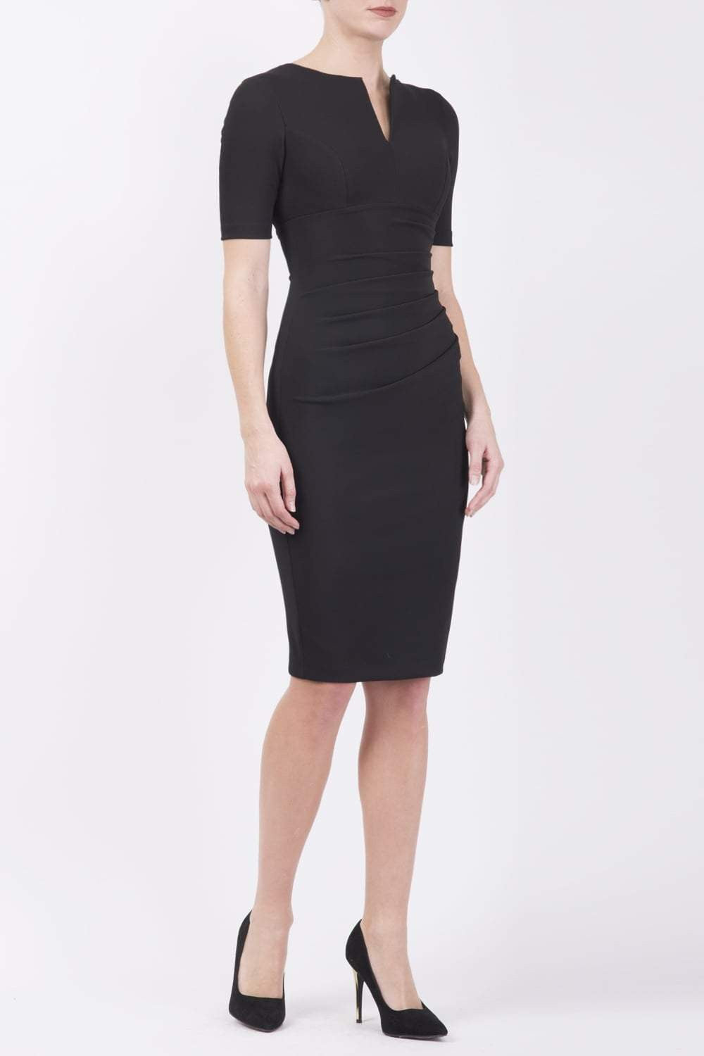 blonde model is wearing diva catwalk lydia short sleeve pencil fitted dress in black colour with rounded neckline with a slit in the middle front